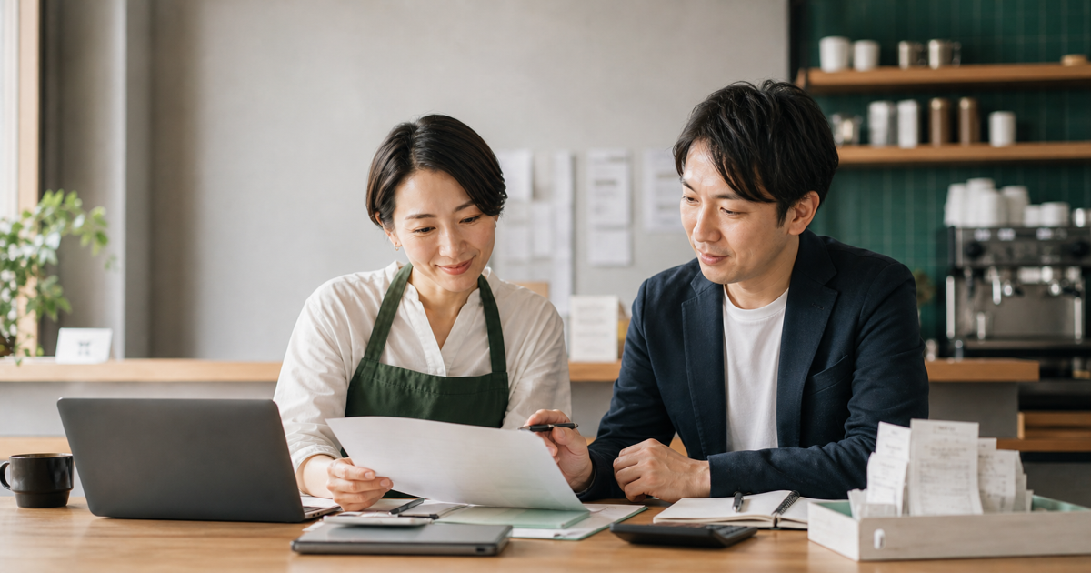 Hospitality operator and accountant reviewing export paperwork together at a cafe counter.